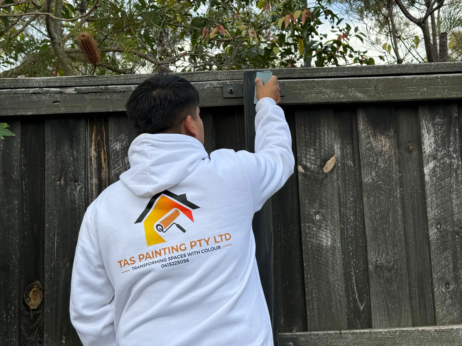 Painter sanding a timber fence ready for restoration