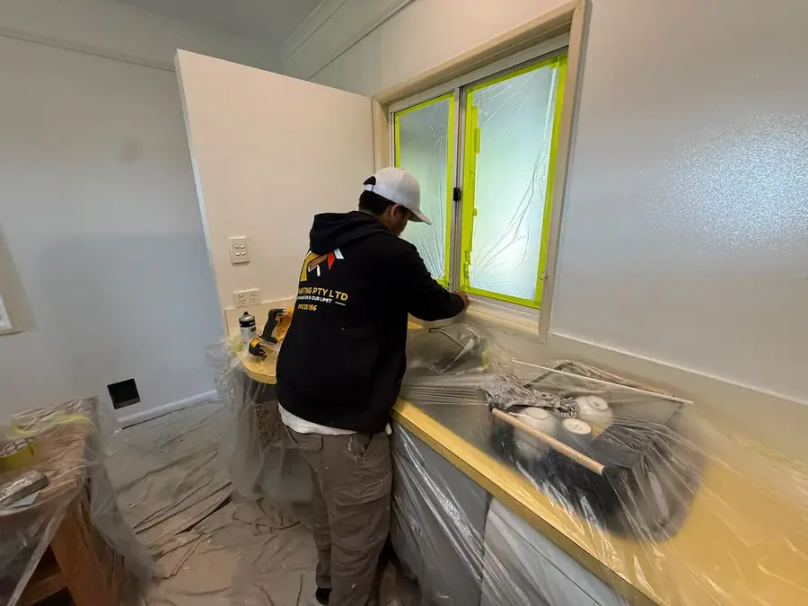 Painter working near a kitchen window during preparation