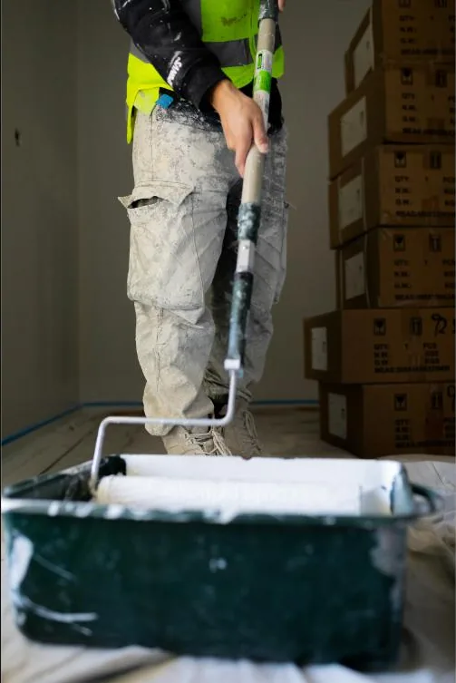 Painter preparing a room with drop sheets and paint tray