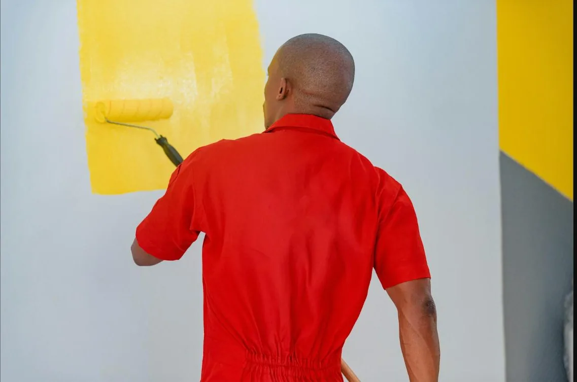 Painter applying fresh coat of paint to a wall