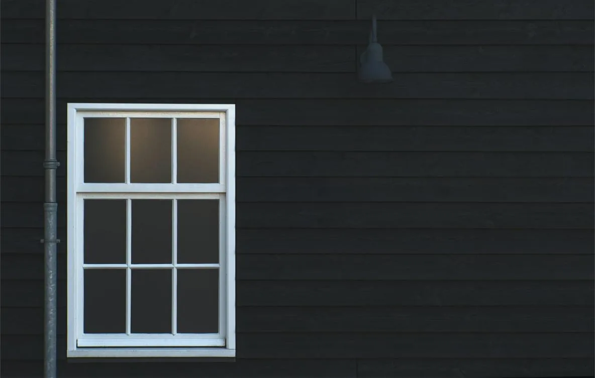 Freshly painted white timber window frame against dark cladding